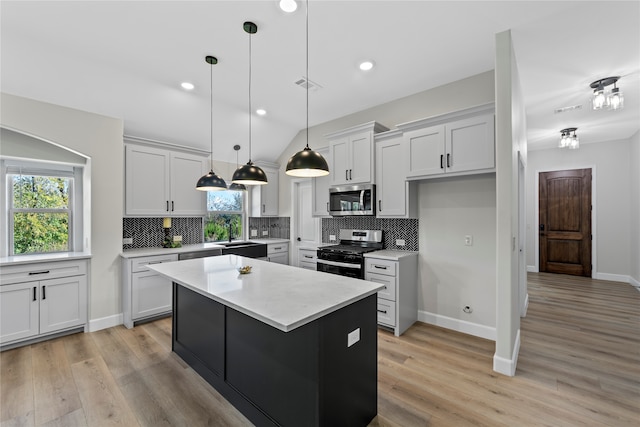 kitchen with decorative backsplash, appliances with stainless steel finishes, light wood-type flooring, pendant lighting, and a center island