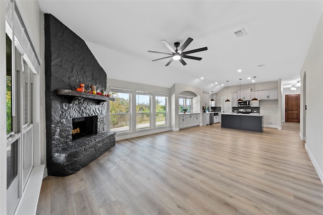 unfurnished living room with ceiling fan, a fireplace, light hardwood / wood-style floors, and vaulted ceiling