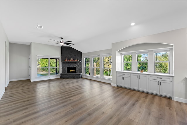 unfurnished living room featuring a fireplace, a healthy amount of sunlight, vaulted ceiling, and light wood-type flooring