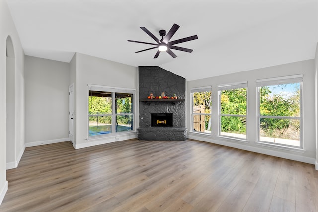 unfurnished living room with plenty of natural light, light hardwood / wood-style floors, a stone fireplace, and vaulted ceiling