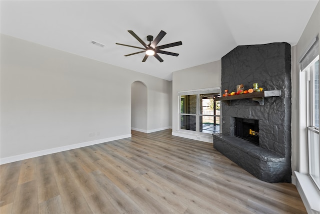 unfurnished living room with a stone fireplace, ceiling fan, light hardwood / wood-style floors, and vaulted ceiling