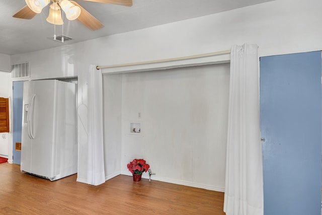 unfurnished bedroom with white refrigerator with ice dispenser, light wood-type flooring, and ceiling fan