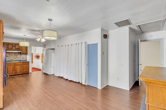 kitchen with white fridge, wood-type flooring, tasteful backsplash, and hanging light fixtures