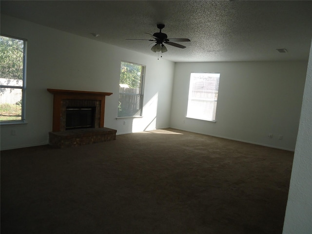 unfurnished living room with ceiling fan, a brick fireplace, carpet, and a textured ceiling