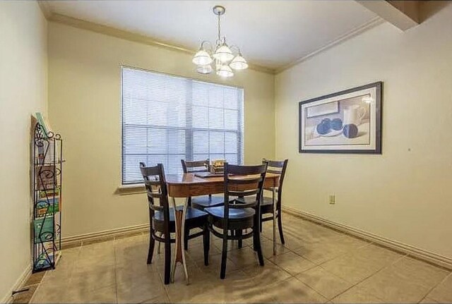 dining area with crown molding, light tile patterned flooring, and a notable chandelier