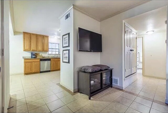 kitchen with dishwasher, sink, light tile patterned floors, and crown molding