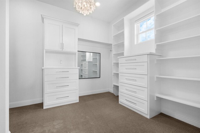 walk in closet featuring dark carpet and a notable chandelier