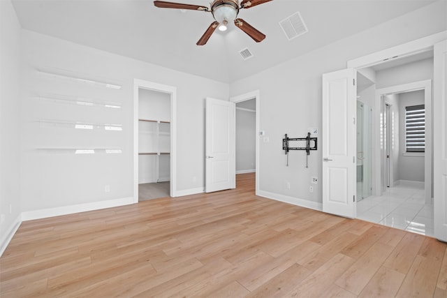 unfurnished bedroom with a spacious closet, ceiling fan, light wood-type flooring, and a closet