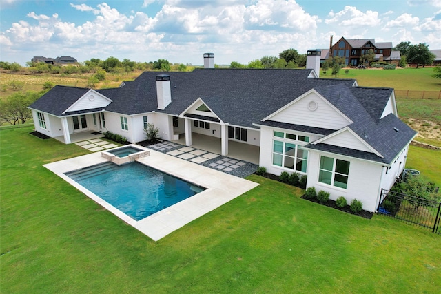 rear view of house with a lawn, a swimming pool with hot tub, and a patio