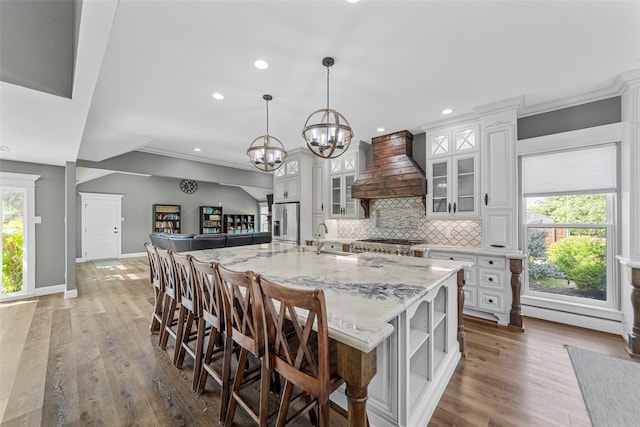 kitchen featuring custom range hood, pendant lighting, white cabinets, and a spacious island