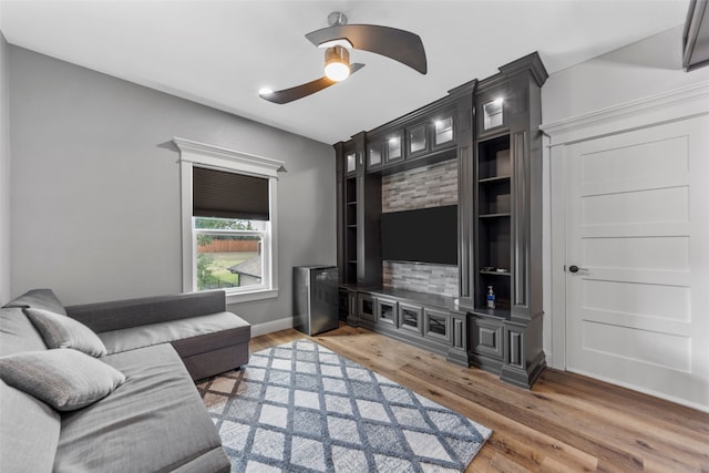 living room featuring wood-type flooring, ceiling fan, and built in shelves