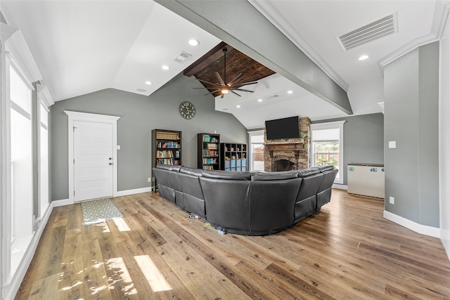 living room with lofted ceiling, a stone fireplace, light hardwood / wood-style floors, and ceiling fan