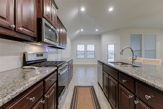 kitchen with appliances with stainless steel finishes, tasteful backsplash, dark brown cabinetry, sink, and light hardwood / wood-style floors