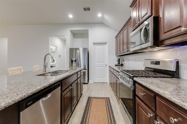 kitchen with backsplash, stainless steel appliances, sink, light hardwood / wood-style floors, and lofted ceiling