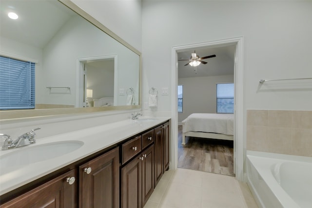 bathroom with vanity, vaulted ceiling, tile patterned flooring, ceiling fan, and a washtub