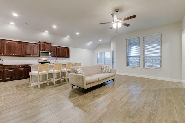 living room featuring ceiling fan, lofted ceiling, and light wood-type flooring