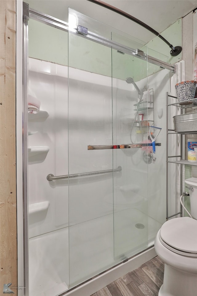 bathroom featuring toilet, wood-type flooring, and walk in shower