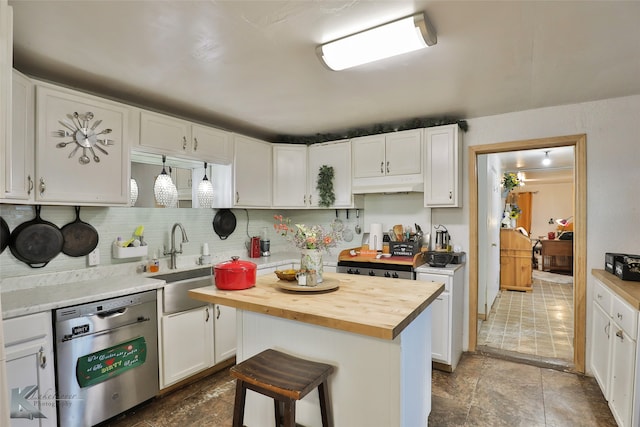 kitchen with wooden counters, white cabinets, sink, stainless steel dishwasher, and a breakfast bar area