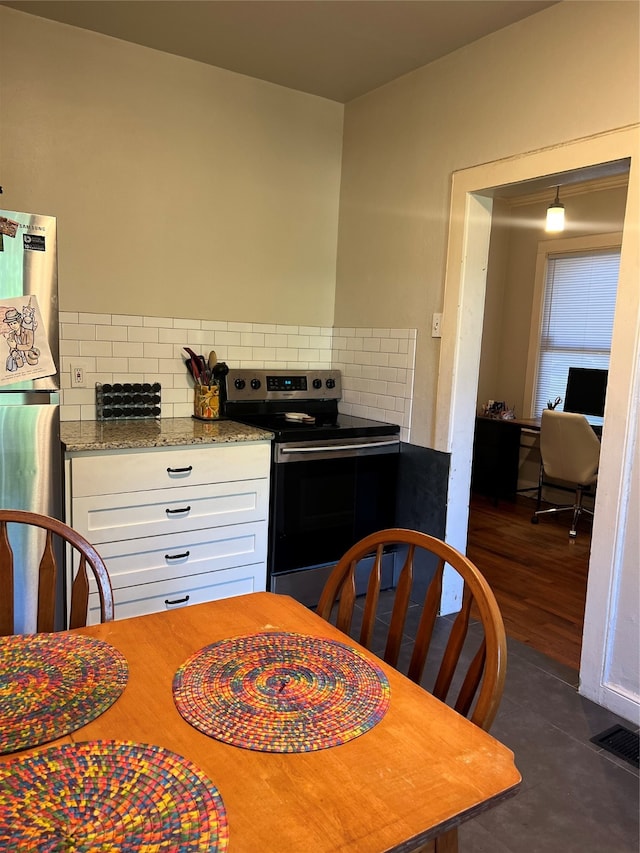 kitchen with light stone countertops, appliances with stainless steel finishes, dark hardwood / wood-style flooring, decorative backsplash, and white cabinetry