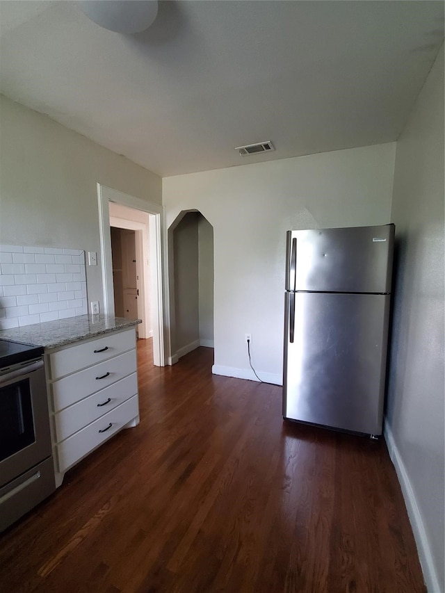 kitchen with decorative backsplash, appliances with stainless steel finishes, light stone counters, dark wood-type flooring, and white cabinetry