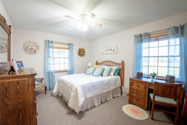 bedroom featuring a textured ceiling, light colored carpet, and ceiling fan