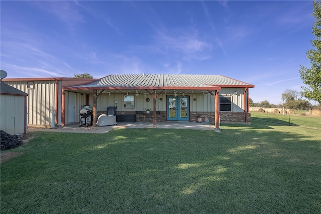 back of property with a lawn, a patio area, and french doors