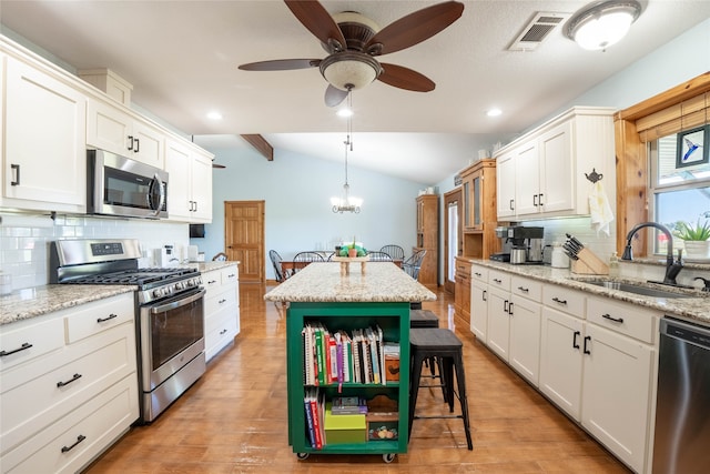 kitchen with a center island, lofted ceiling with beams, sink, light hardwood / wood-style flooring, and appliances with stainless steel finishes