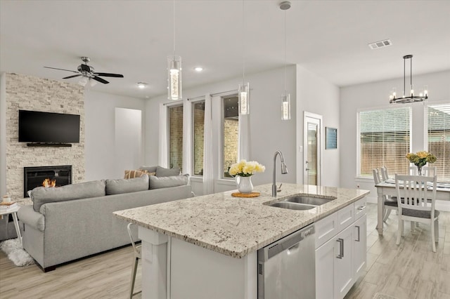 kitchen featuring dishwasher, sink, decorative light fixtures, a kitchen island with sink, and white cabinets