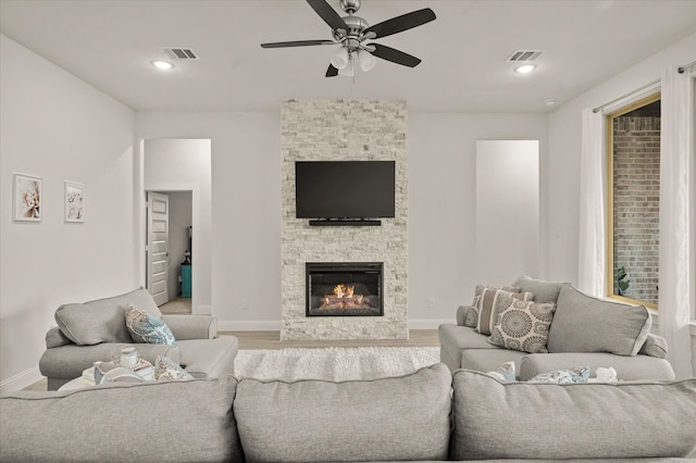 living room featuring ceiling fan, a fireplace, and light hardwood / wood-style flooring