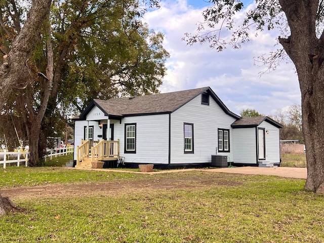 rear view of property featuring central air condition unit and a yard