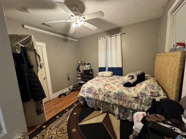 bedroom featuring ceiling fan, wood-type flooring, and a textured ceiling