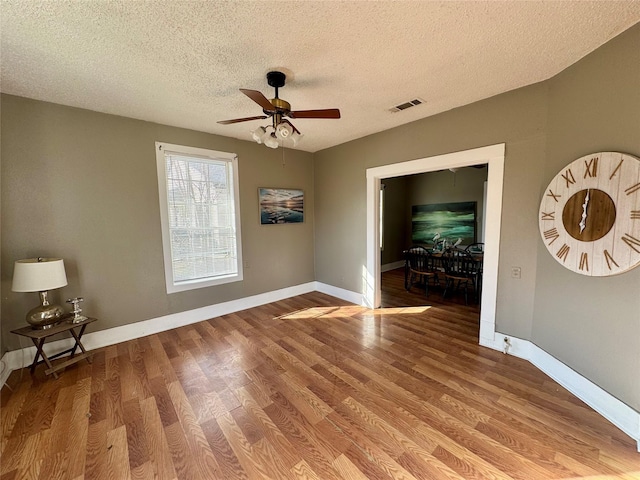 spare room featuring ceiling fan, hardwood / wood-style floors, and a textured ceiling