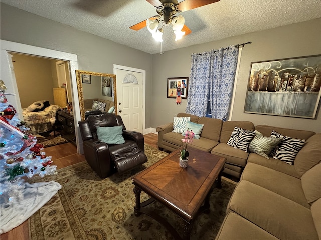 living room with ceiling fan, a textured ceiling, and dark wood-type flooring