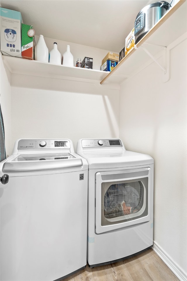 laundry area featuring washing machine and dryer and light hardwood / wood-style flooring