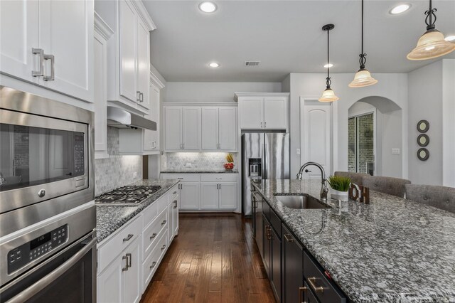 kitchen featuring white cabinetry, sink, decorative light fixtures, and appliances with stainless steel finishes