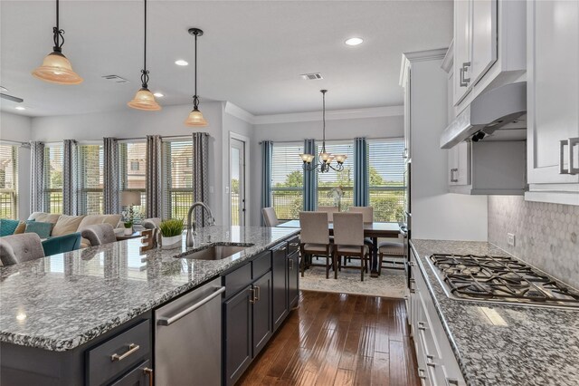 kitchen with stainless steel appliances, sink, an inviting chandelier, dark hardwood / wood-style floors, and an island with sink