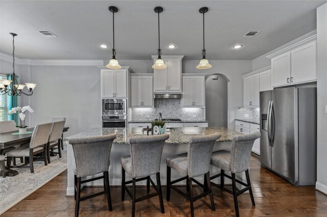 kitchen featuring stainless steel appliances, white cabinetry, and hanging light fixtures