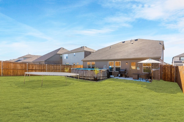 back of house with a patio area, a fenced in pool, a trampoline, and a yard