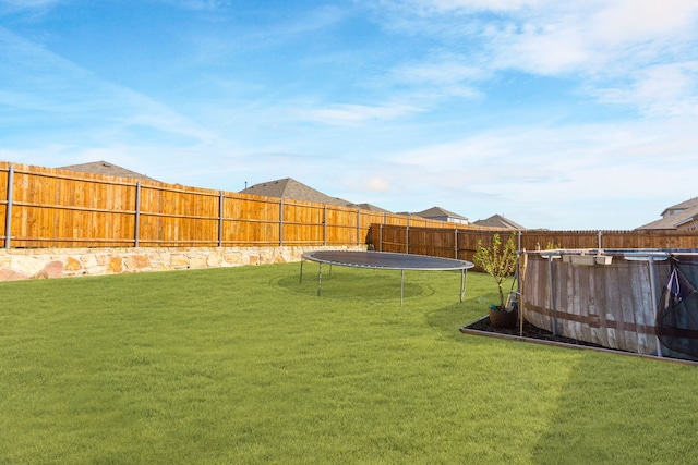 view of yard featuring a trampoline and a swimming pool