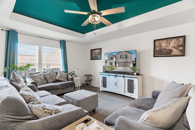 living room featuring dark hardwood / wood-style floors, ceiling fan, and a raised ceiling