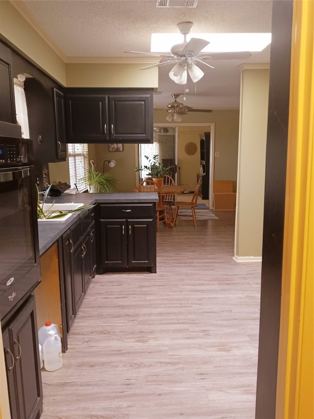 kitchen with visible vents, dark countertops, light wood-style flooring, dark brown cabinets, and black oven