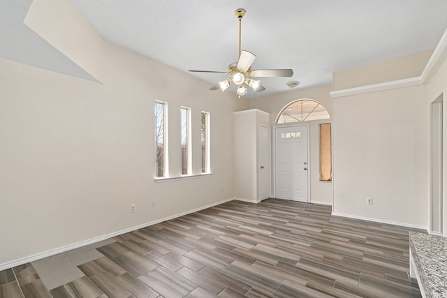 foyer with ceiling fan, dark wood-type flooring, and a textured ceiling