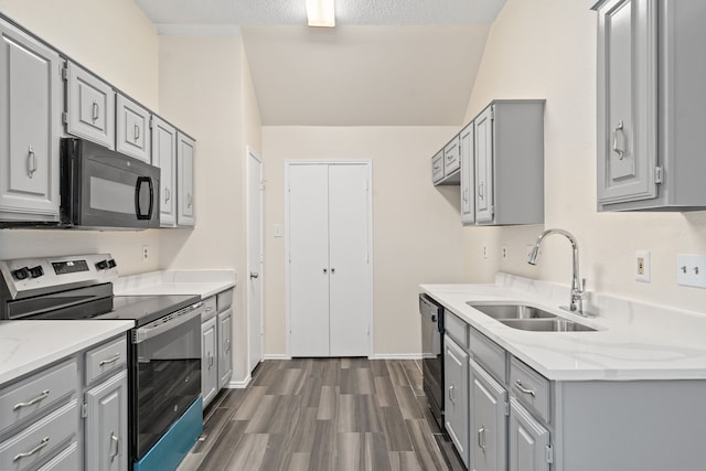 kitchen featuring a textured ceiling, dark wood-type flooring, sink, black appliances, and lofted ceiling