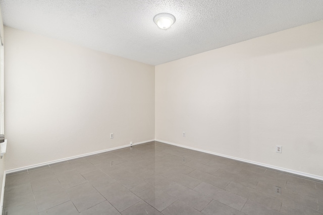 tiled empty room with a textured ceiling