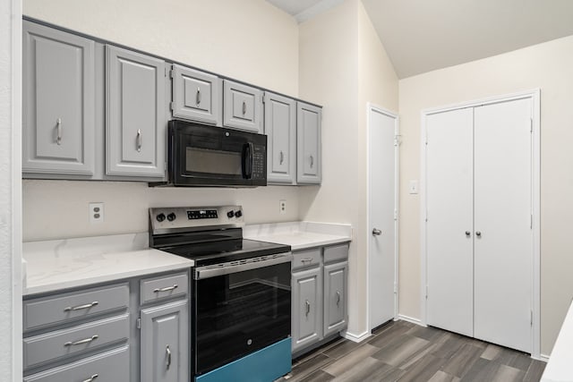 kitchen featuring gray cabinets, light stone counters, stainless steel range with electric cooktop, and dark wood-type flooring