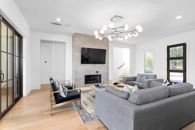 living room with a tiled fireplace, light hardwood / wood-style flooring, and a notable chandelier