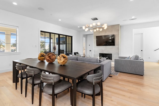 dining area with light wood-type flooring and a tiled fireplace