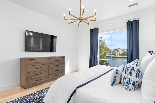 bedroom featuring access to exterior, wood-type flooring, and an inviting chandelier