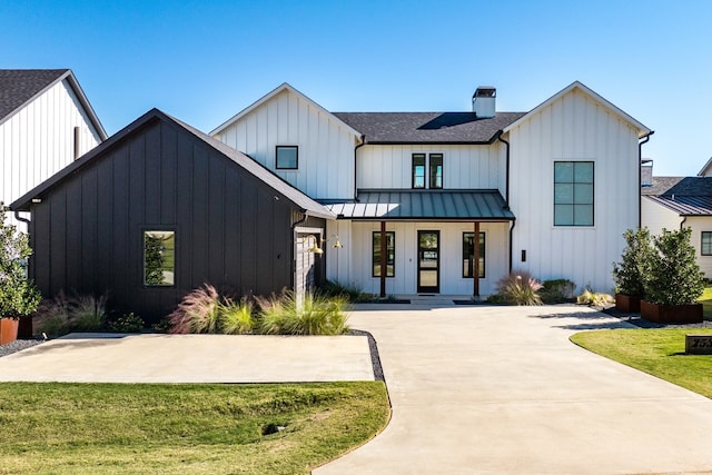 modern farmhouse featuring covered porch and a front yard