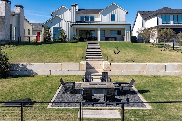 rear view of property featuring a fire pit, a patio area, and a lawn